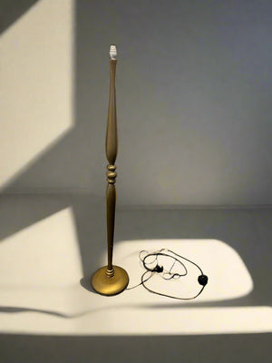 Gold candlestick with a white candle on a gray surface