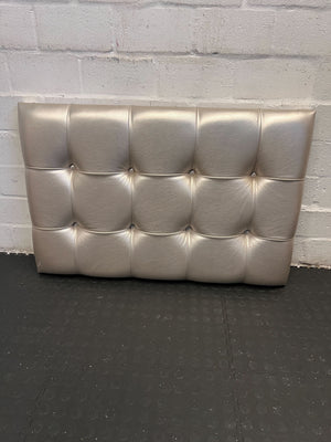 Silver tufted headboard against a gray brick wall.