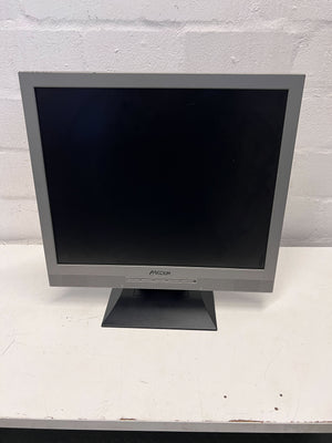 Monitor with a gray frame on a white surface against a light gray brick wall.
