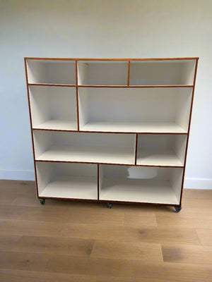 White bookshelf with brown trim against a white brick wall.