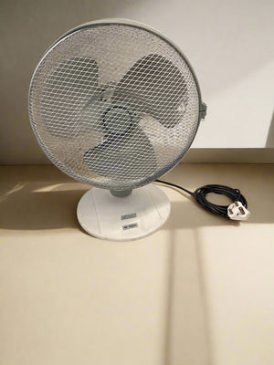 Tabletop fan on a white surface with a gray brick wall background