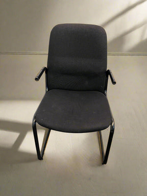 Black office chair on a light wooden floor with a neutral wall background
