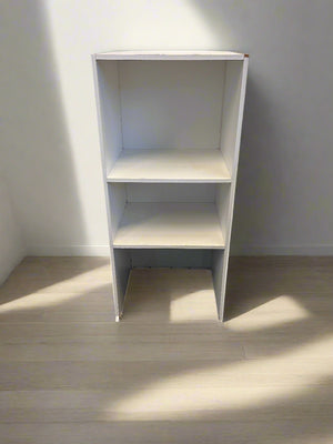 White bookshelf against a plain wall with a light wood floor.