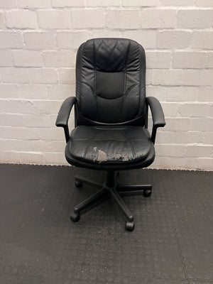 Black office chair with visible wear against a white brick wall.