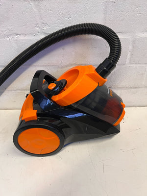 Black and orange vacuum cleaner on a white floor with a light gray wall background