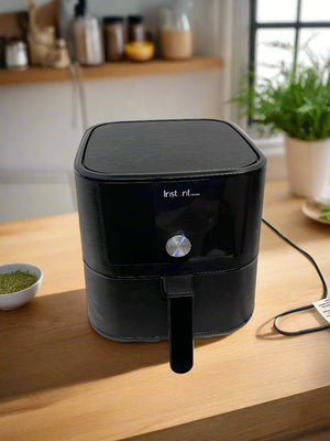 Black air fryer on a white surface with a gray brick wall background