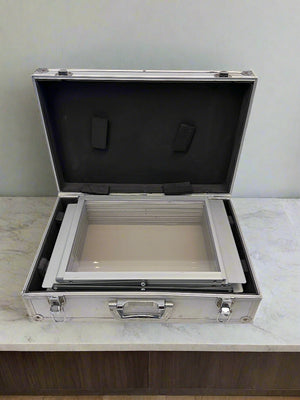 Open metallic case with glass insert on a light gray background