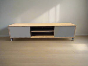 Wooden TV stand with gray doors on a wooden floor.