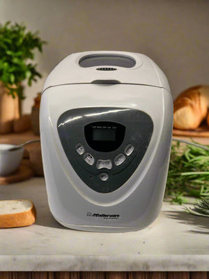 White bread maker on a kitchen counter with bread and herbs in the background