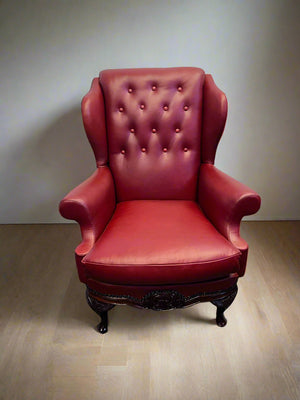 Red leather armchair on a wooden floor with a plain wall background