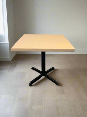 Light wooden table with black metal base on a neutral background