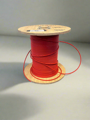 Spool of red wire on a wooden reel against a gray background