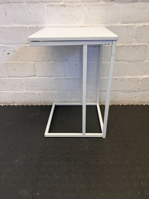 Small white table against a gray brick wall.