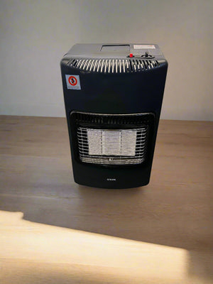 Black portable heater on a black surface with a gray brick wall background