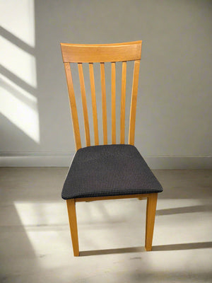 Wooden chair with a black cushion on a plain floor and wall background