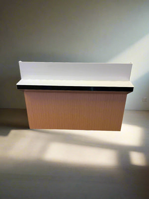 Reception desk with a white backrest against a white brick wall.