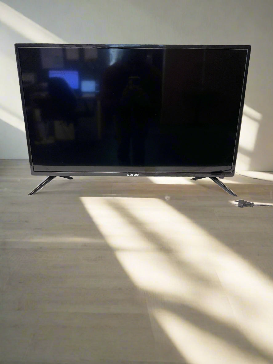 Black TV on a white table against a white brick wall