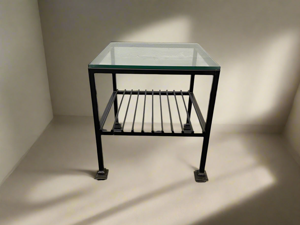 A black frame glass top side table with a visible metal structure, placed against a white background.