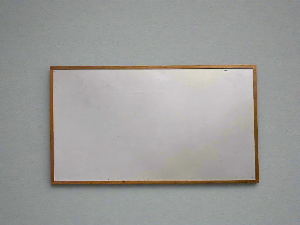 A grey wooden framed notice board with a cracked texture, leaning against a white brick wall.