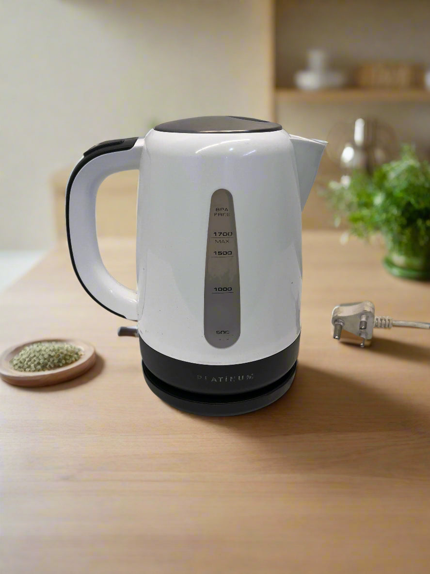 White electric kettle on a wooden surface with a blurred kitchen background