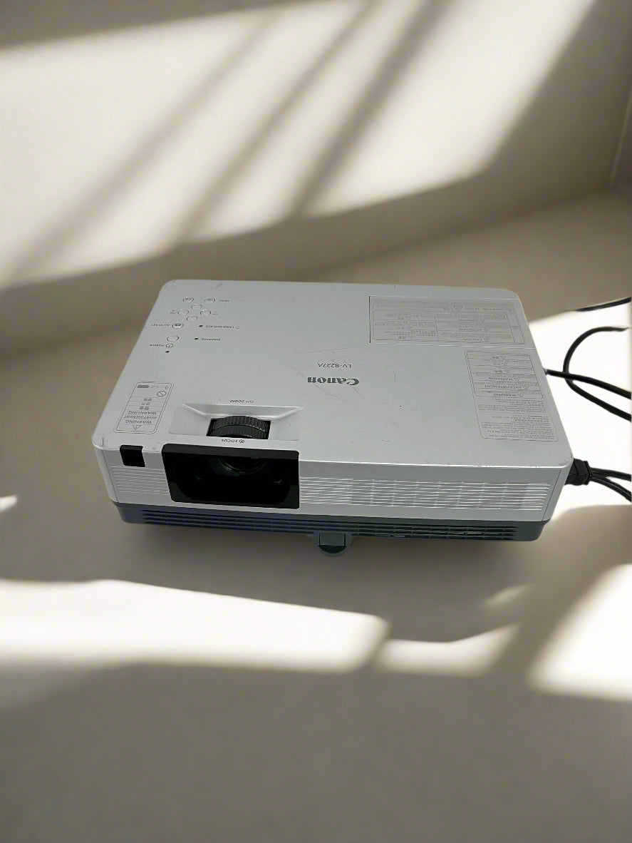 Canon projector on a light-colored surface with shadows cast by a window.