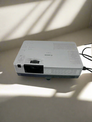 Canon projector on a light-colored surface with shadows cast by a window.