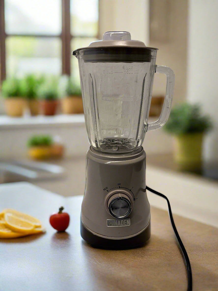 Gray blender on a kitchen counter with fruits and plants in the background