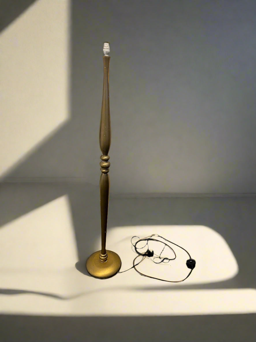 Gold candlestick with a white candle on a gray surface