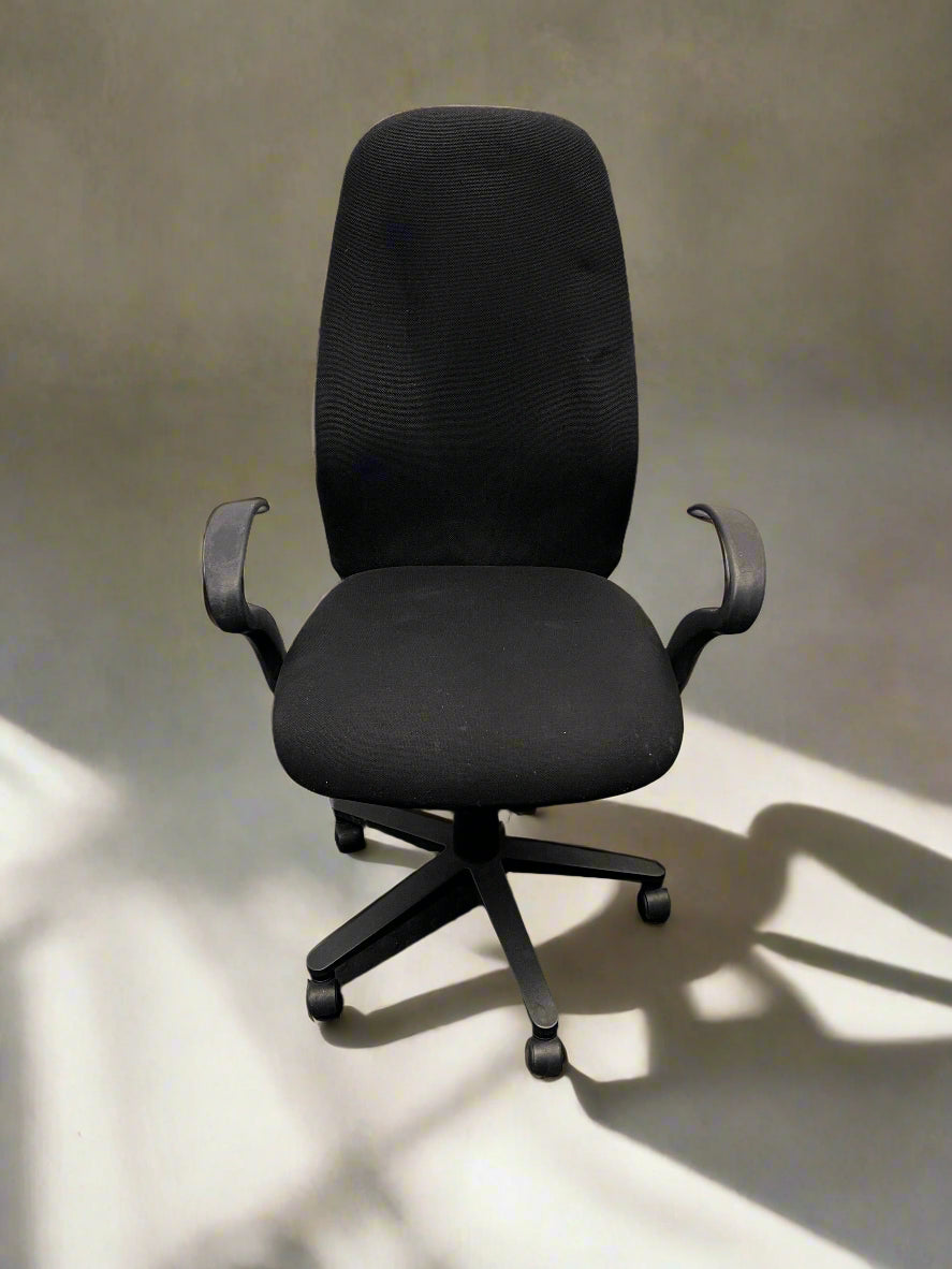 Black office chair on a light floor with a neutral wall background