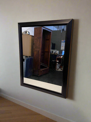 Rectangular mirror with dark frame on a light-colored wall