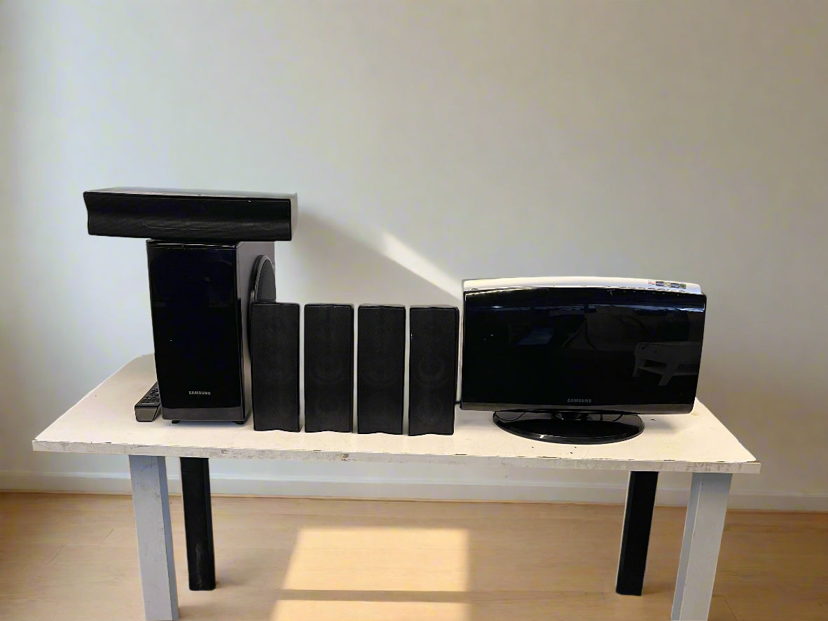 Black home theater system on a white table against a plain wall.