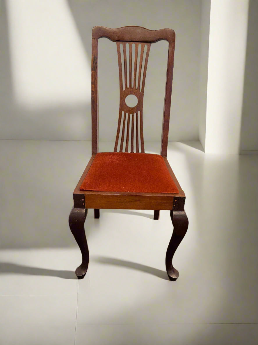 Wooden chair with a red cushion on a black surface and white brick wall background