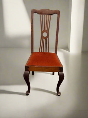 Wooden chair with a red cushion on a black surface and white brick wall background