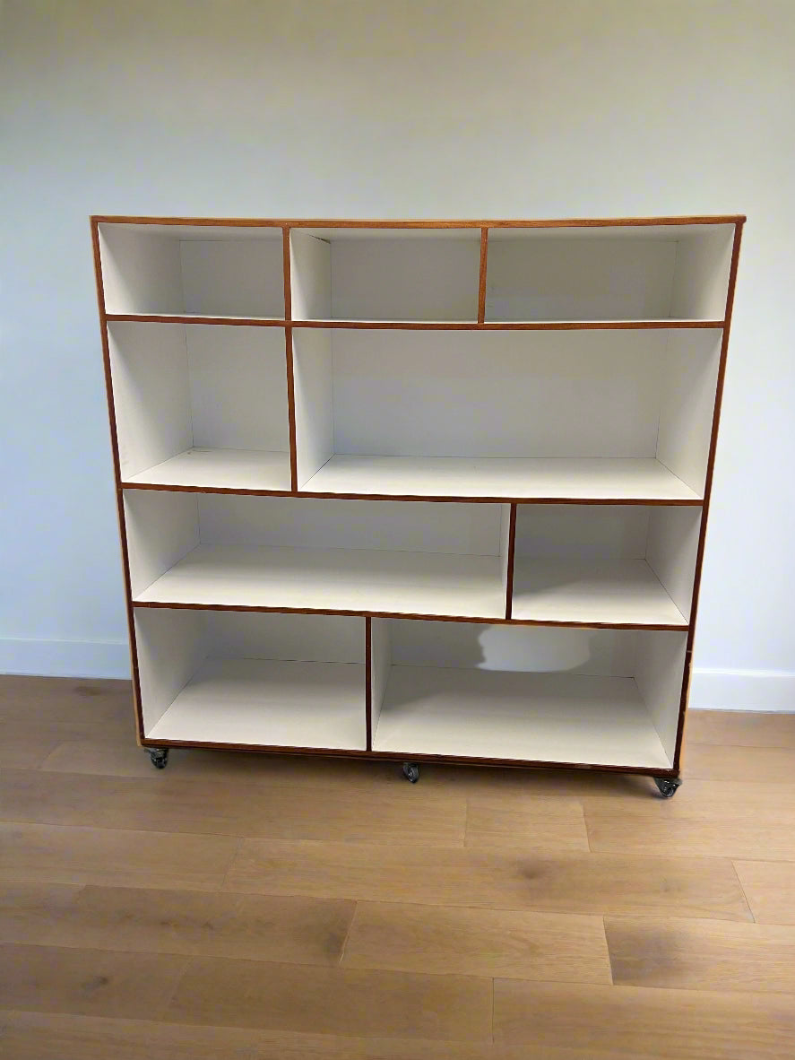 White bookshelf with brown trim against a white brick wall.