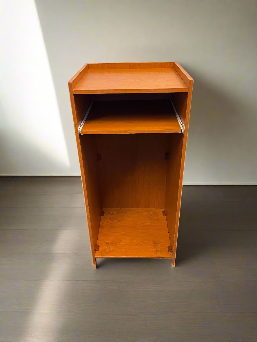 Orange metal cabinet against a white brick wall.