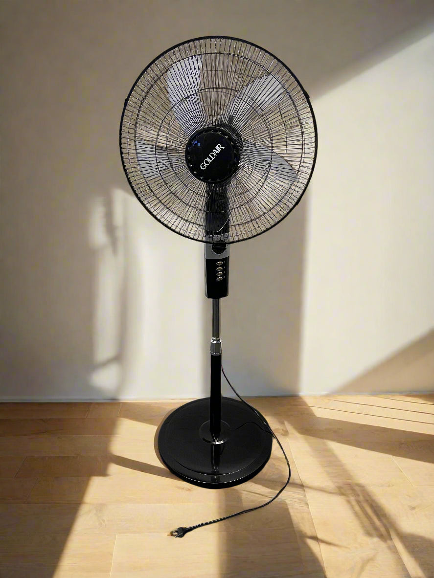 Black standing fan against a white brick wall.