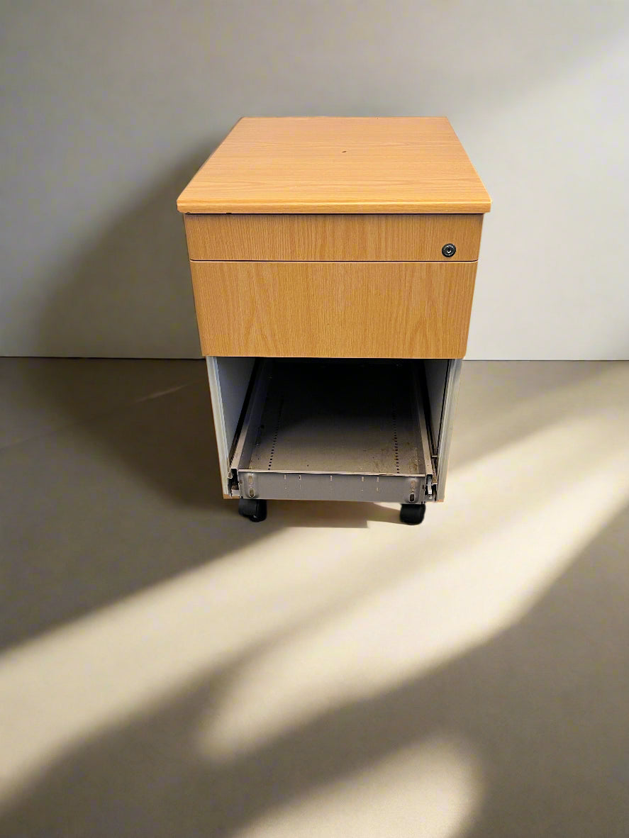 Wooden desk with a drawer on a black floor against a gray brick wall