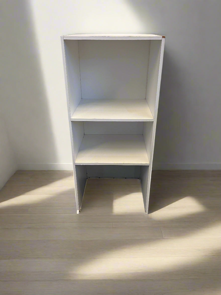 White bookshelf against a plain wall with a light wood floor.
