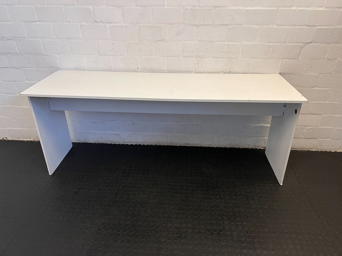 White desk against a white brick wall.