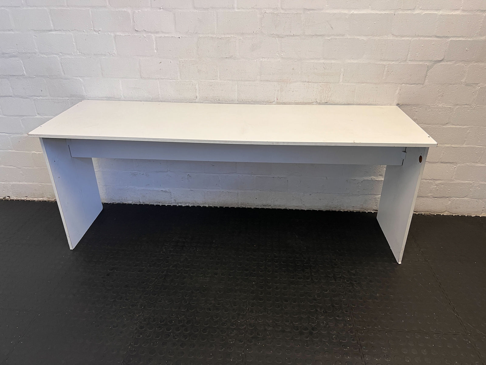 White desk against a white brick wall.