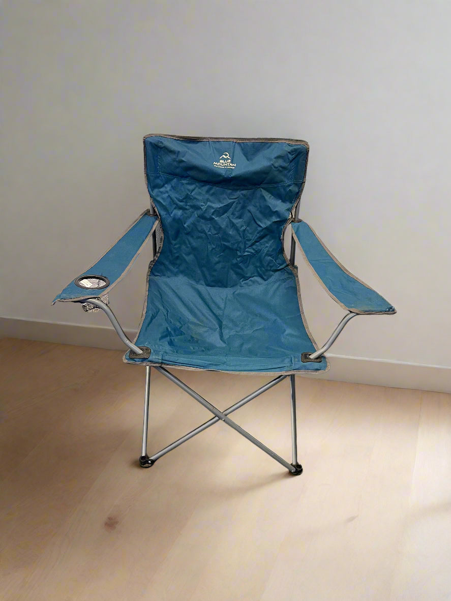 Blue folding chair with cup holder on a wooden floor against a white wall