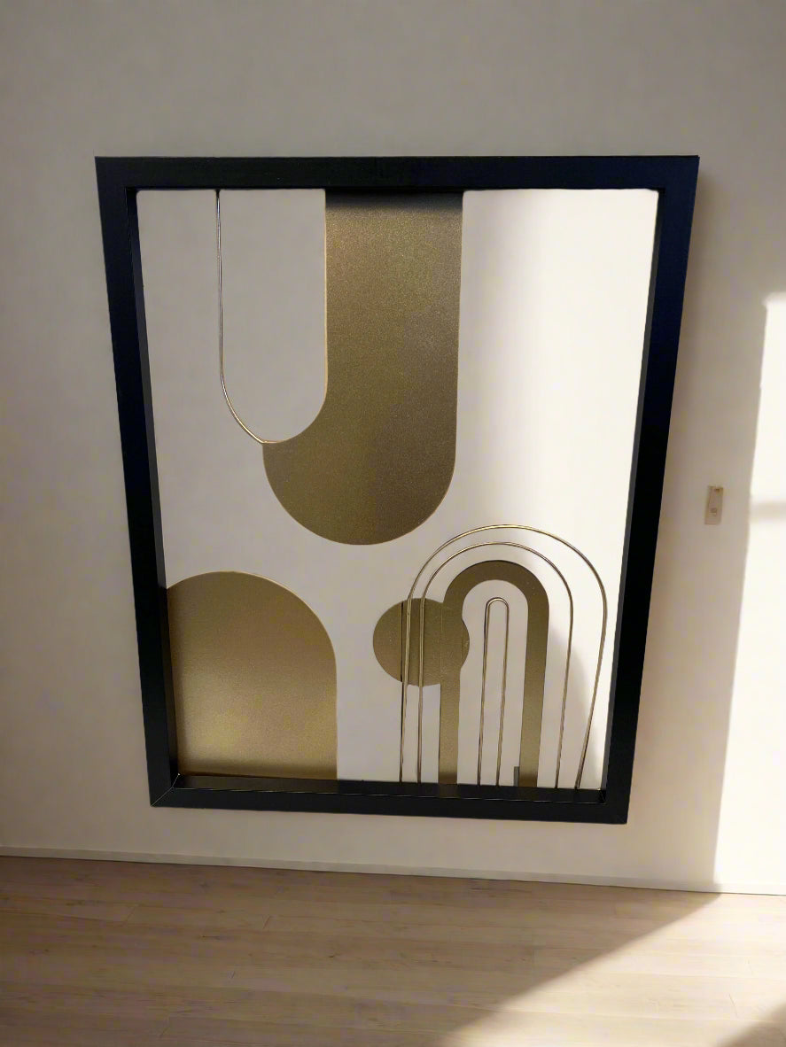 Framed abstract art piece with geometric shapes on a white brick wall background