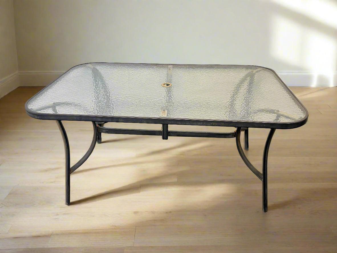 Glass-top patio table with metal frame on a wooden floor