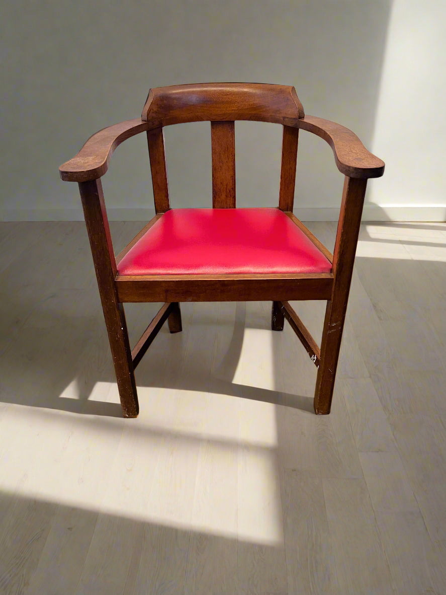 Wooden chair with a red cushion on a gray floor.