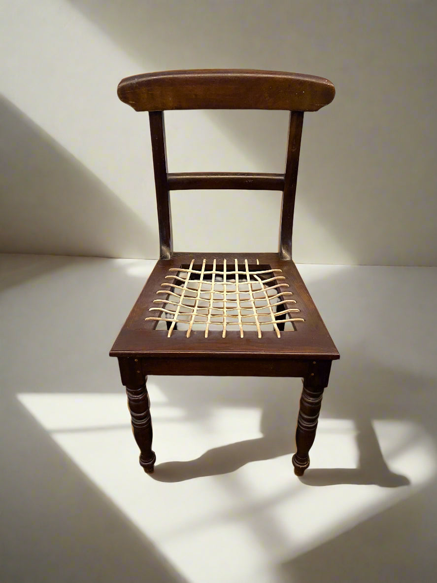 Wooden chair with woven seat on a white floor and light gray wall
