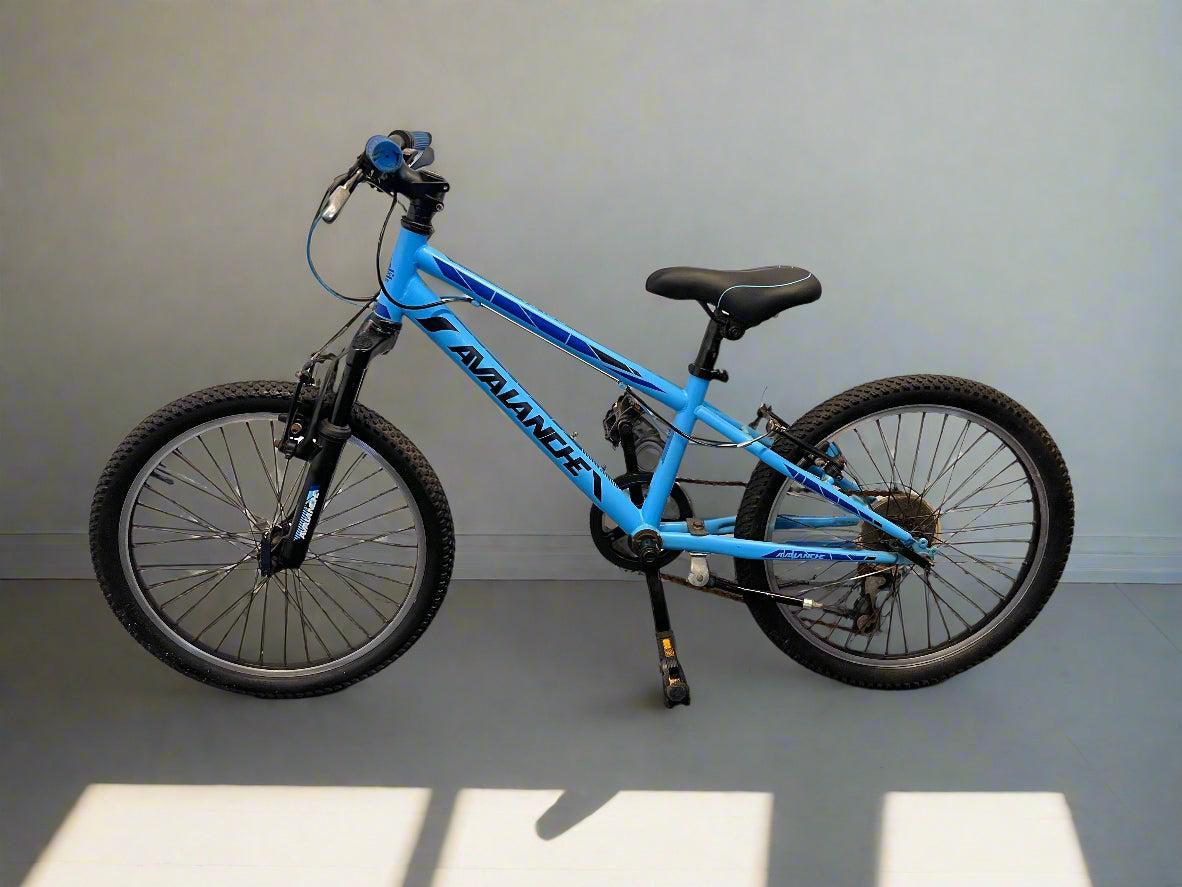 Blue children's bicycle on a gray floor with a white wall background