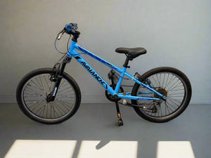 Blue children's bicycle on a gray floor with a white wall background
