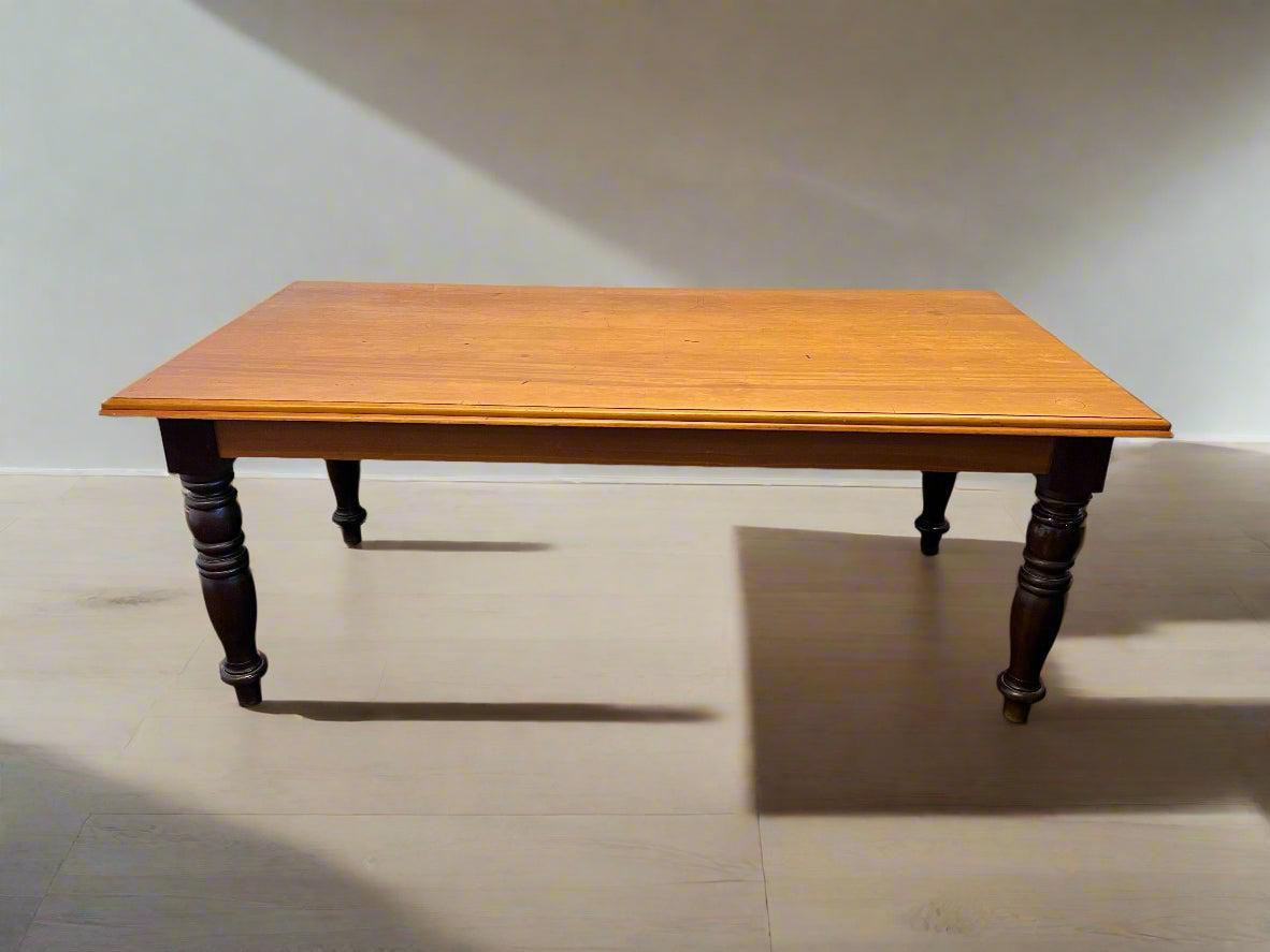 Wooden table with dark legs on a light floor and white wall background