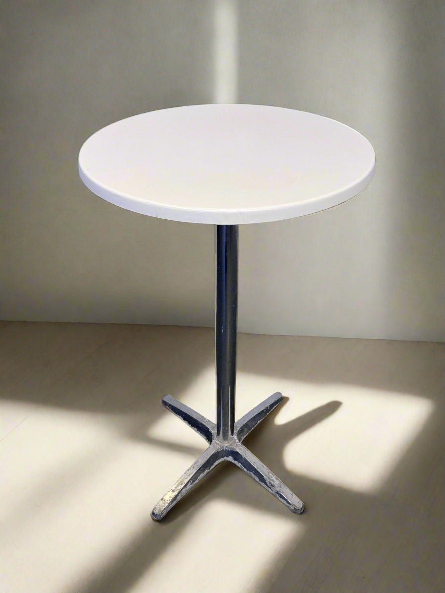 Round white table with a metal base on a plain background
