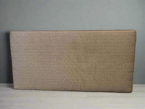 Beige upholstered headboard against a gray wall